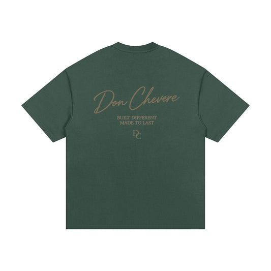 Don Chevere Essential Oversized Heavy Tee in dark green, 100% cotton with a round neck and short sleeves. Features a graphic print on the back.