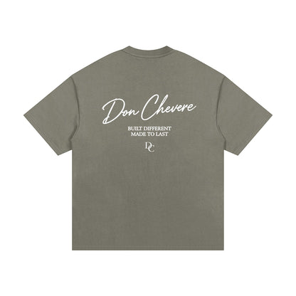 Don Chevere oversized heavy tee in olive green, made of 100% cotton with a crew neck and short sleeves. Features white text print on back.