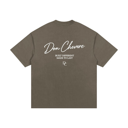 Don Chevere oversized heavy tee in taupe, made of 100% cotton with a round neck and short sleeves. Features a graphic print on the back.